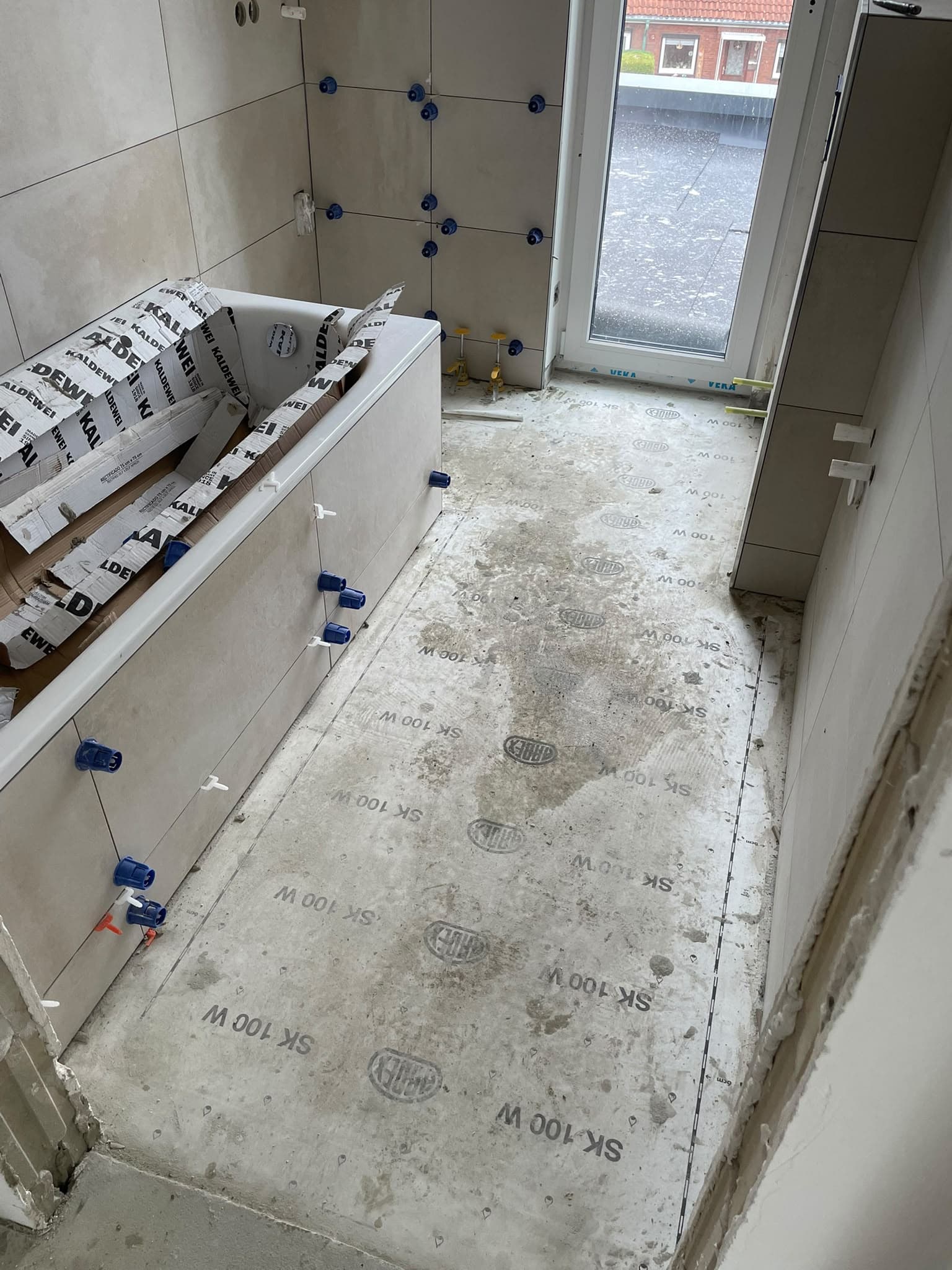 Badezimmer mit gefliesten Wänden und unfertigem Boden
