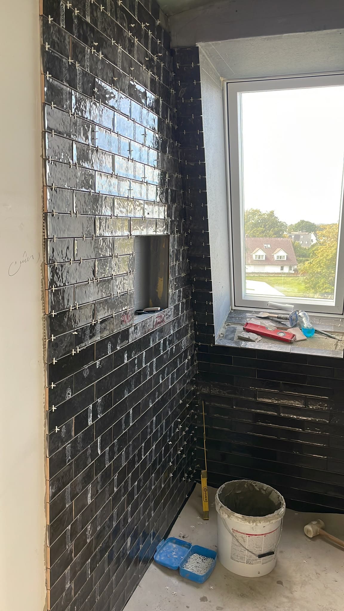 Dunkel geflieste Wände mit Nische neben einem Fenster