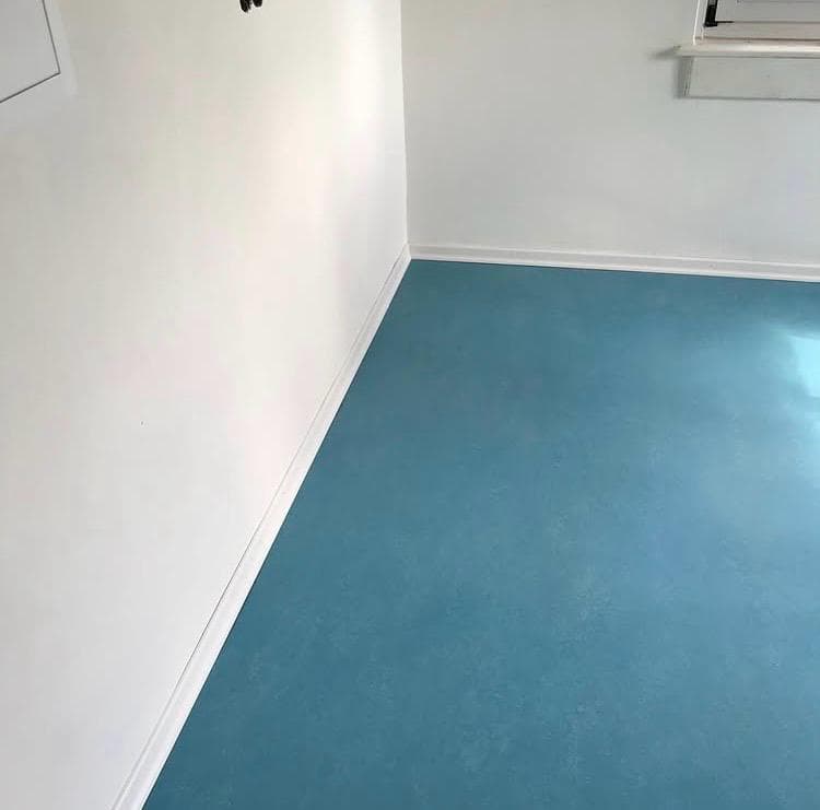 Blauer Bodenbelag entlang einer hellen Wand